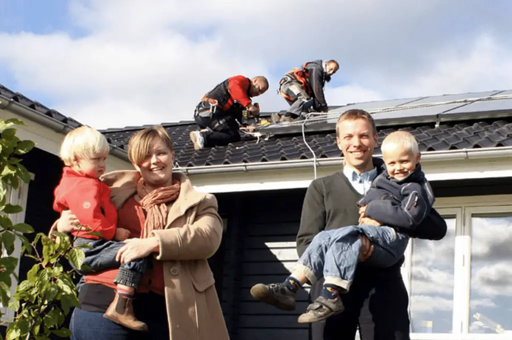 Familien bag Risskov Teknik og Solar foran deres hjem med solcelleanlæg.